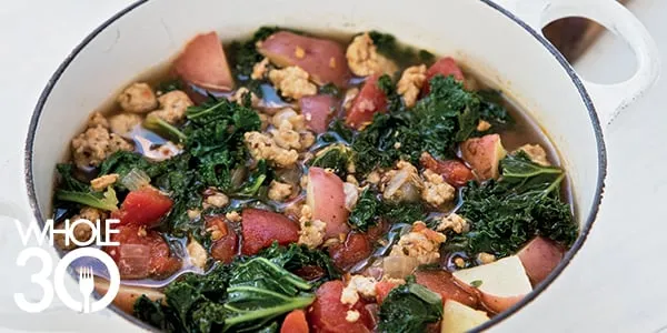 A large dutch oven filled with steaming Whole30 Sausage Potato and Kale Soup