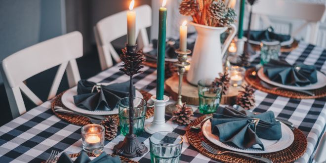A kitchen table with a blue checkered table cloth with blue candles, and five place settings