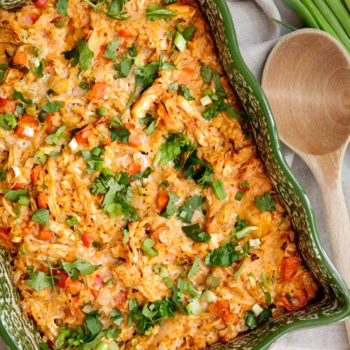 buffalo chicken casserole in a green dish with a wooden spoon next to the dish