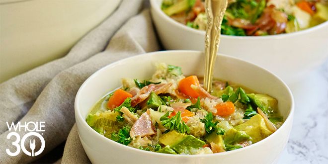 A bowl of chicken soup with veggies. In the bottom left corner is a white Whole30 logo.
