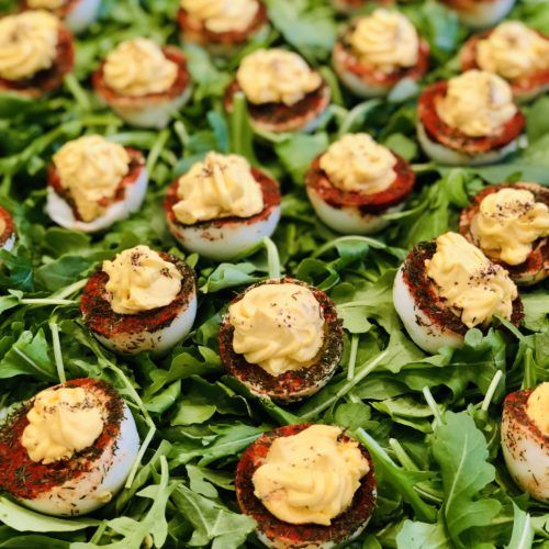 Deviled eggs with herbs and spices on a bed of greens