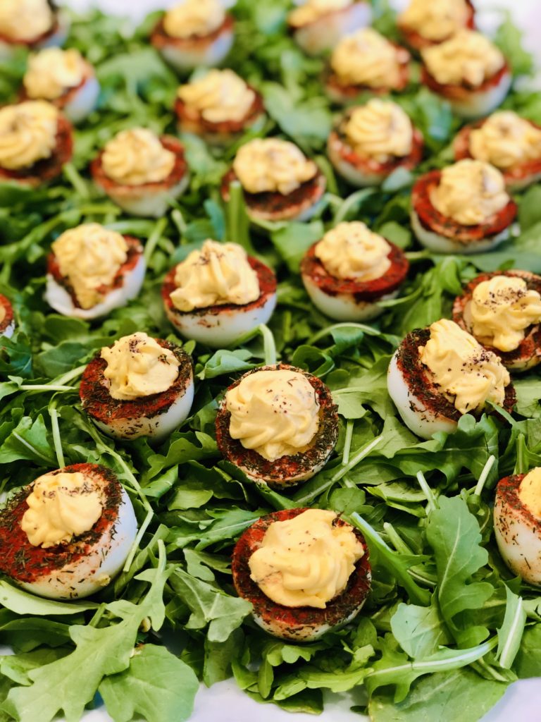 Deviled eggs with herbs and spices on a bed of greens
