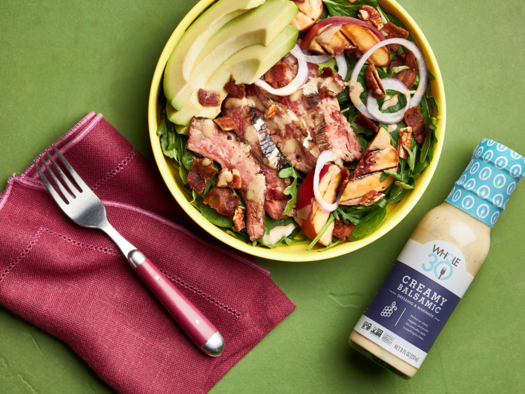 Whole30 Grilled Steak and Peach Salad next to a bottle of Whole30 Creamy Balsamic