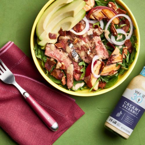 Whole30 Grilled Steak and Peach Salad next to a bottle of Whole30 Creamy Balsamic