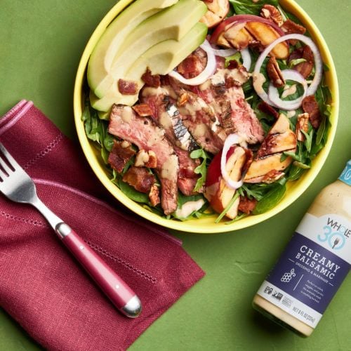 Whole30 Grilled Steak and Peach Salad next to a bottle of Whole30 Creamy Balsamic