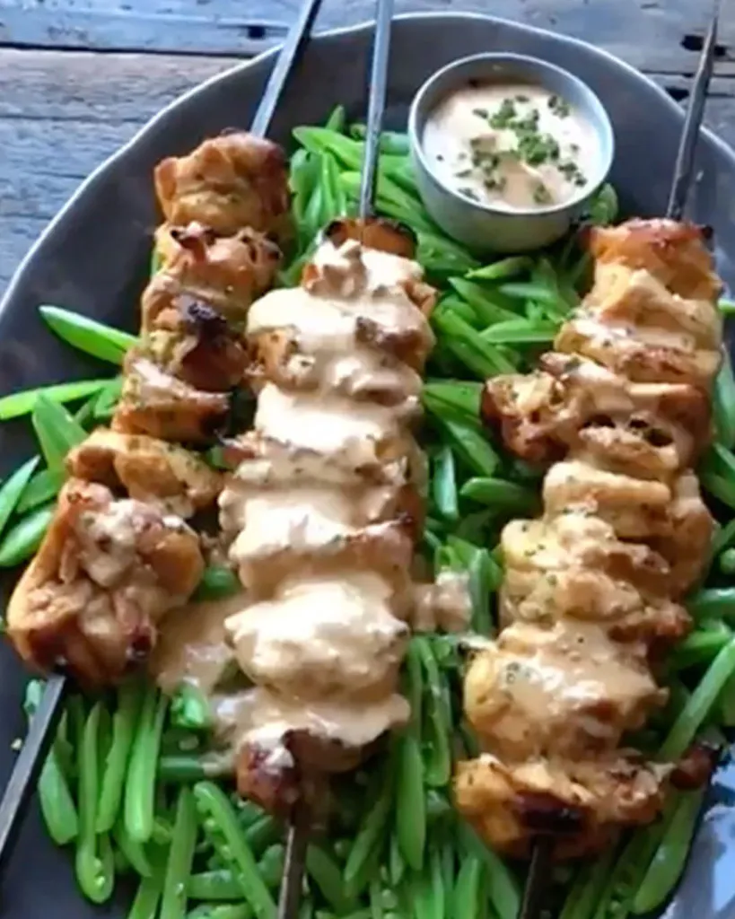 A plate with three Whole30 Chicken Kabobs with Spicy Almond Sauce