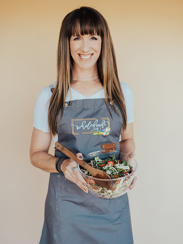 Digital Content Producer, Autumn Michaelis wearing an apron and holding a bowl of fresh salad smiling at the camera.