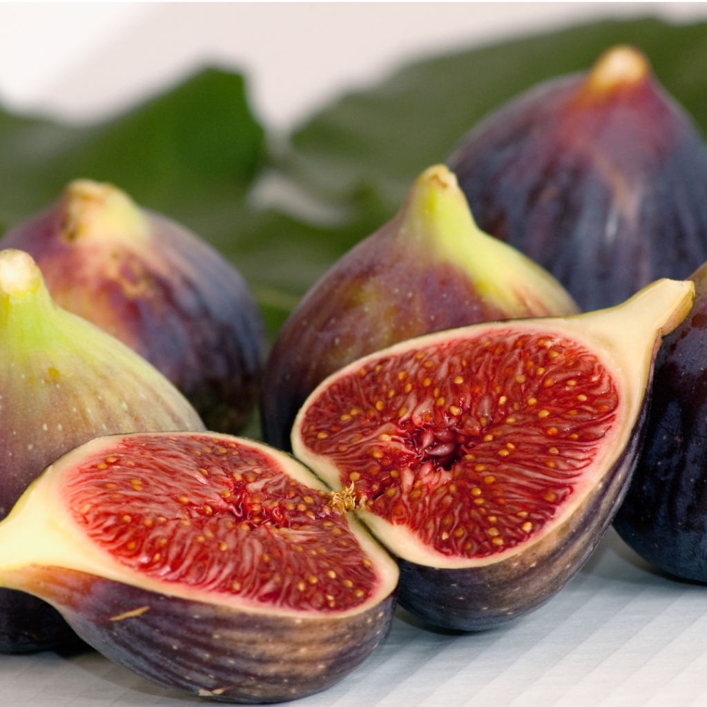 An image of a fig cut open, with whole figs in the background. 