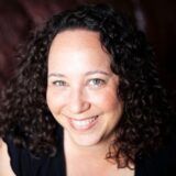 A close up shot of Ashley Maynard. She smiles and looks at the camera.