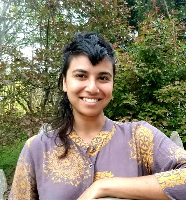 Cynthu Muthusamy smiling at the camera in front of trees
