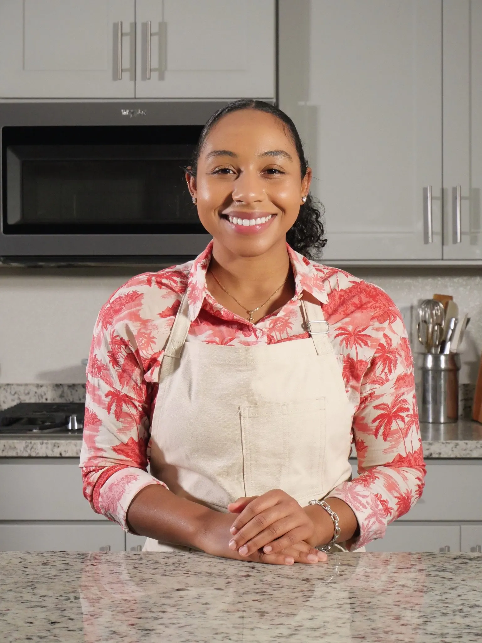 Kai Kani is a pink shirt and white apron, smiling at the camera.