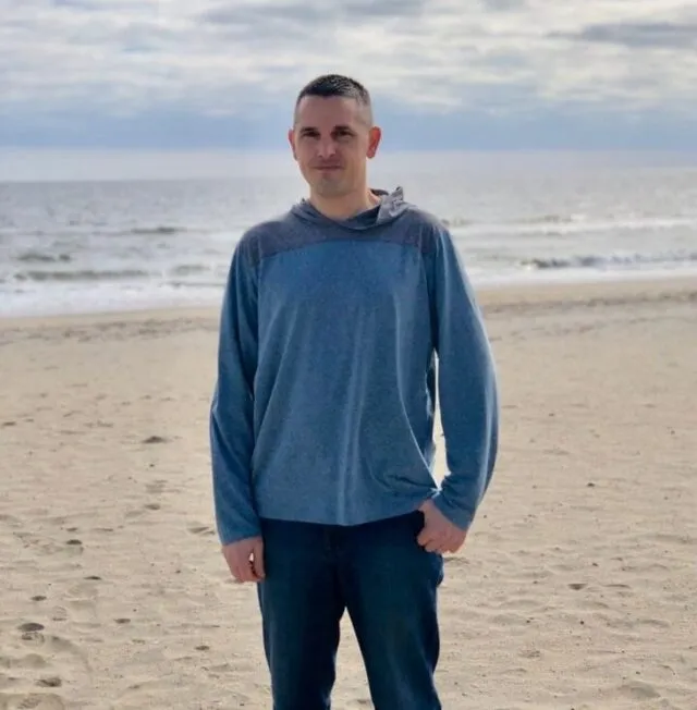 Tim standing and smiling at the beach