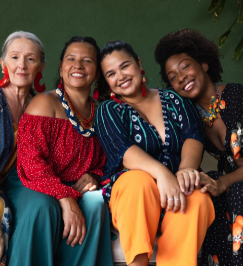 A group of women sitting together, smiling at the camera.
