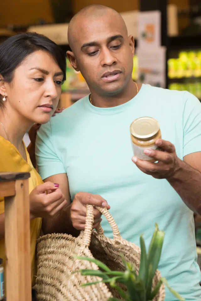 A couple in a grocery store reading the food label on a food can.