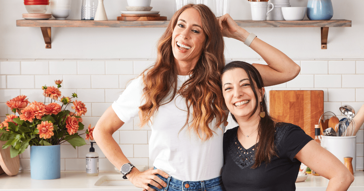 Melissa Urban and Ghazalle Badiozamani standing side by side in a kitchen, smiling at the camera