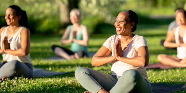 A group of women in the park doing yoga.