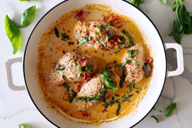 Whole30 Marry Me Chicken in white dish with basil leaf on a marble countertop