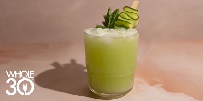 A bright green mocktail with a wavy cucumber ribbon garnish