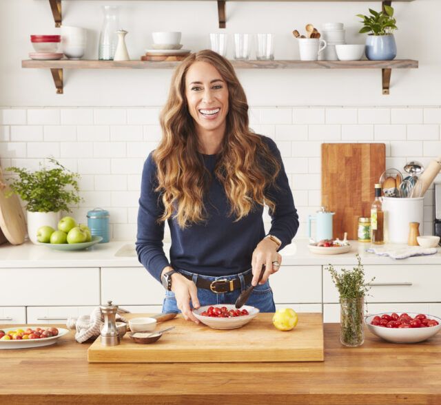 Whole30 CEO Melissa Urban, smiling in a kitchen preparing vegetables