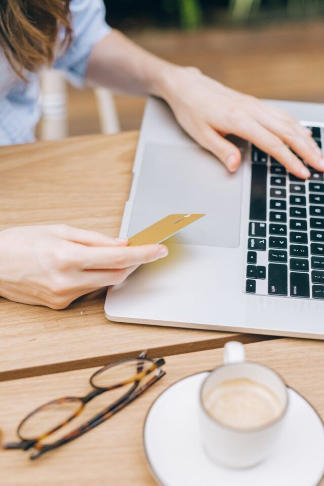 Person holding a payment card while checking out on a laptop